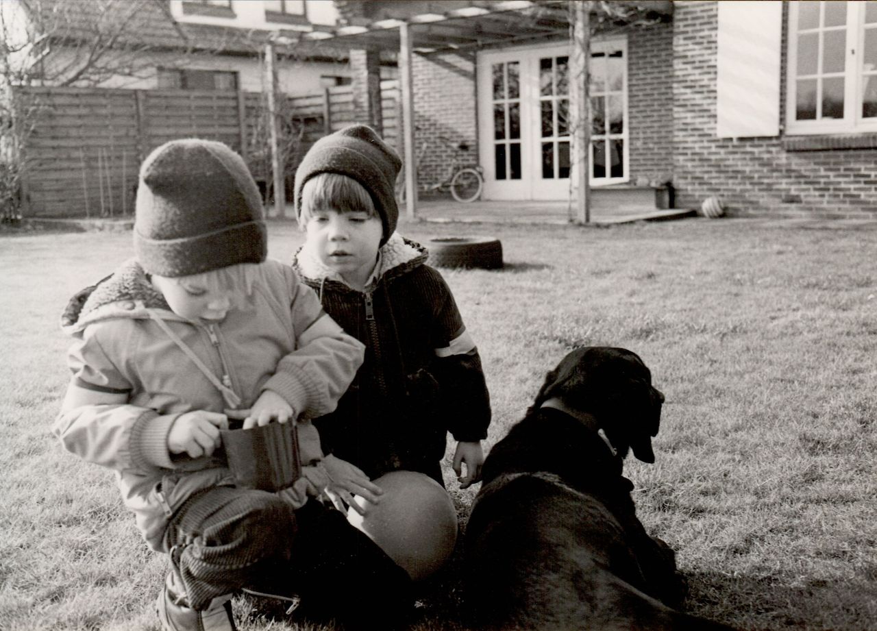 Two children in winter clothes play outside.