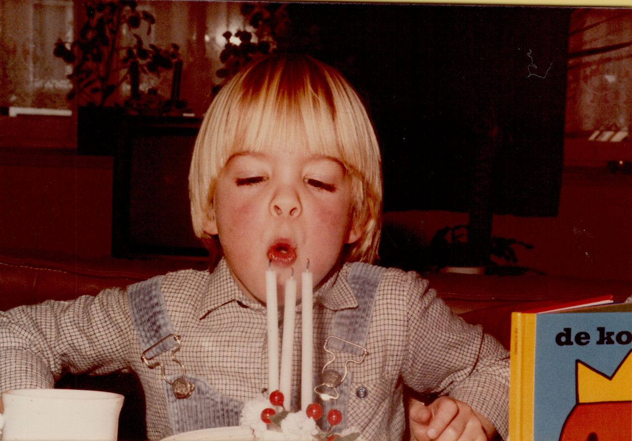 A young child blows out three candles on a birthday cake, celebrating their third birthday.