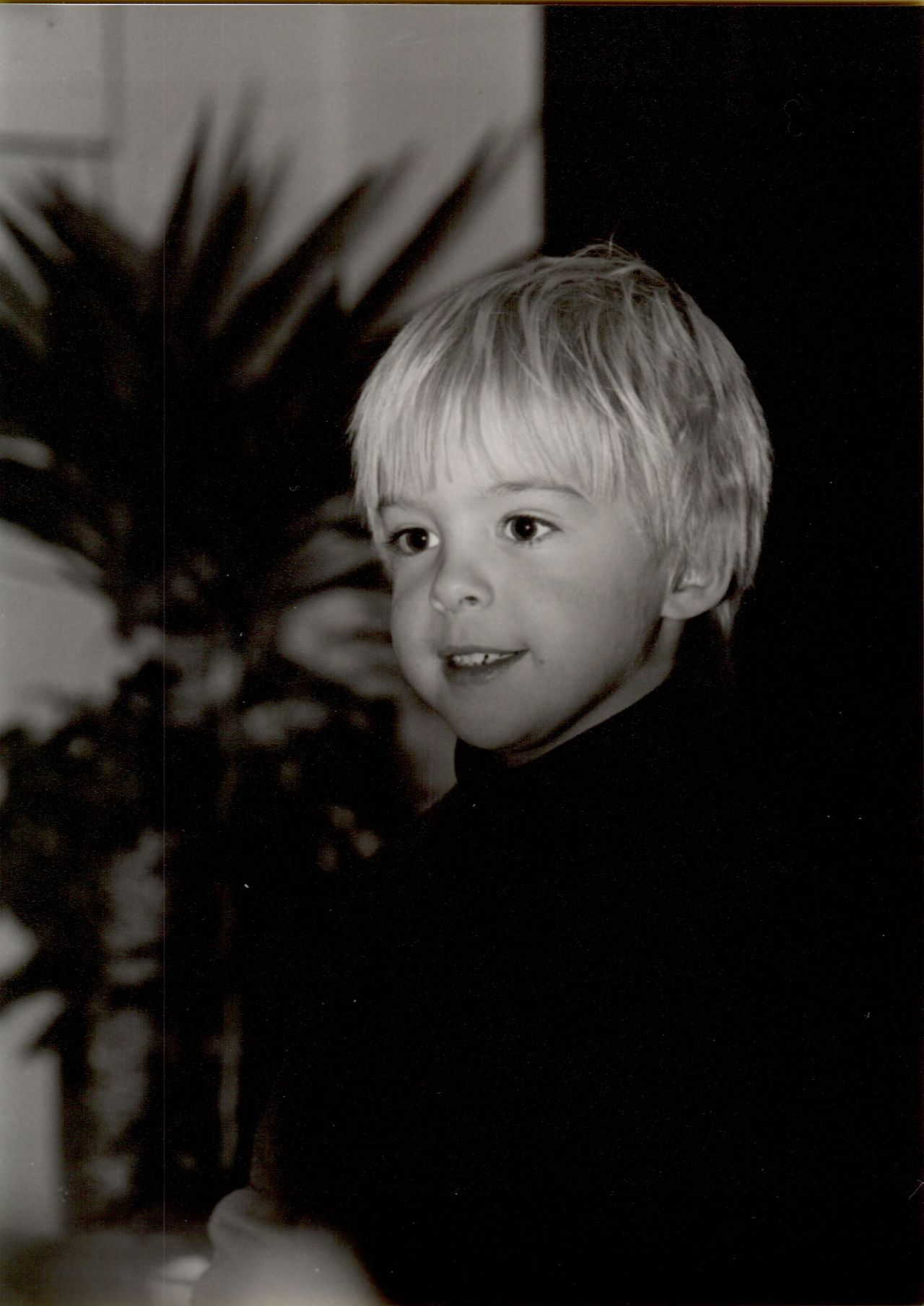 A young child smiles, possibly reacting to receiving a flashlight as a fifth birthday gift.