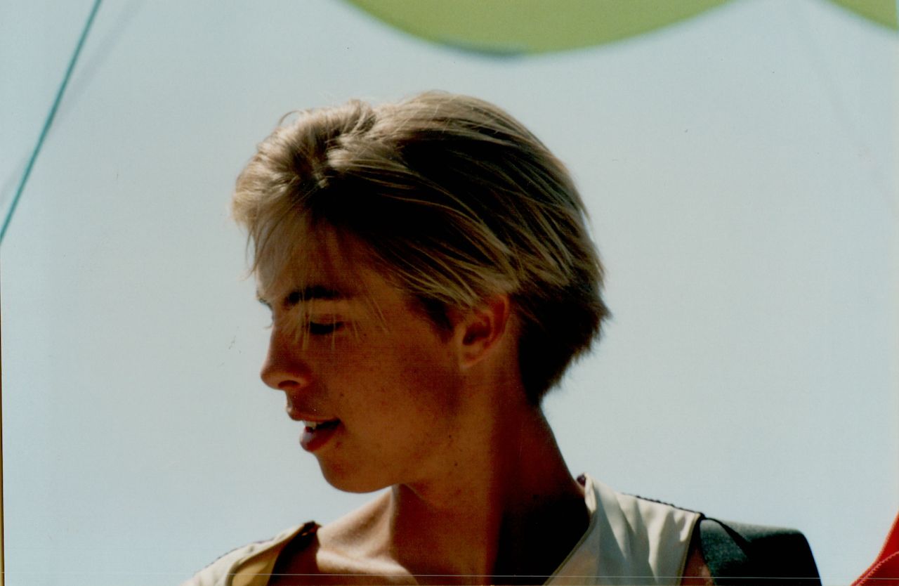 A 15-year-old with wet hair dries off outdoors in Turkey, looking to the side under a bright sky.