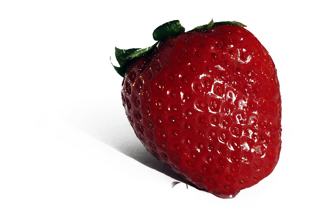 A close-up of a ripe red strawberry with green leaves, set against a white background.