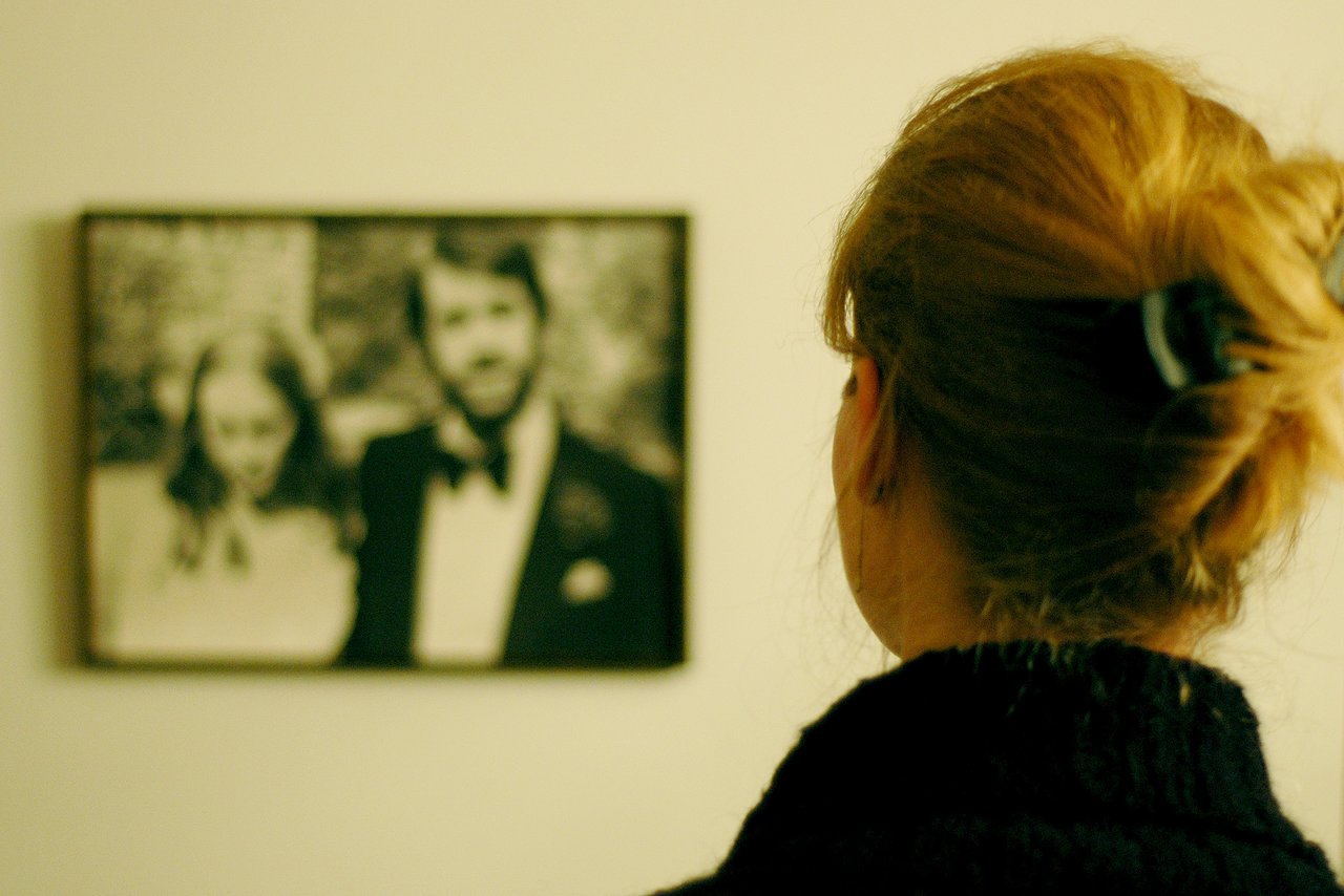 A woman looks at a framed black-and-white wedding photo on the wall.