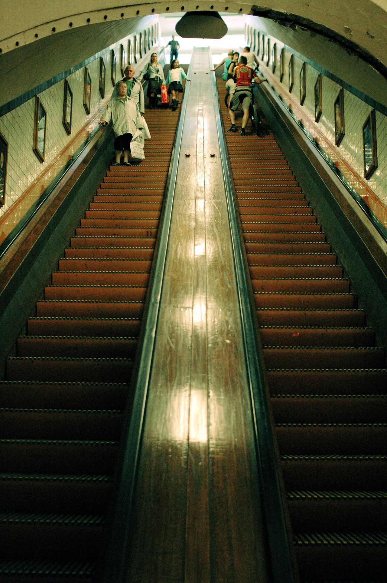 People using the historic wooden escalators in the Sint-Annatunnel, a pedestrian tunnel in Antwerp, Belgium.