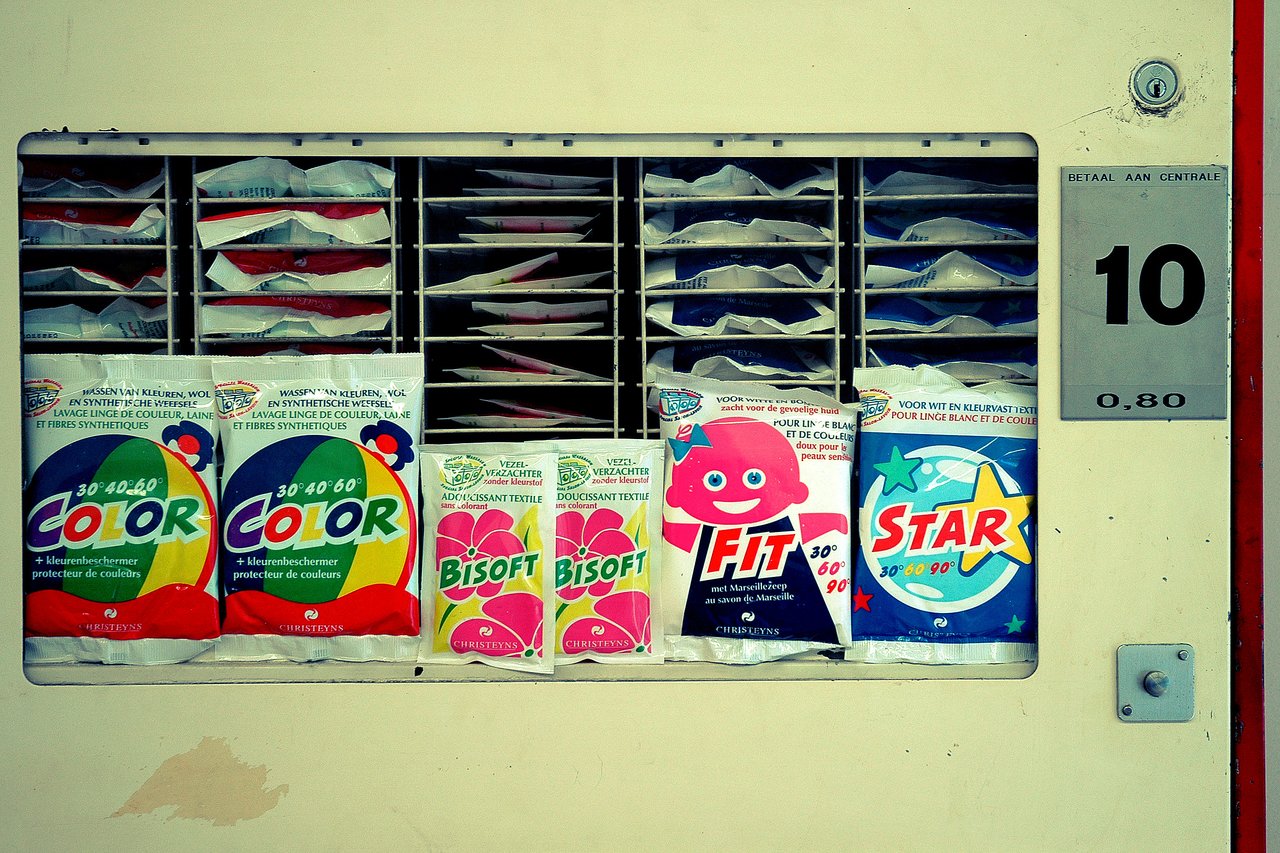 A vending machine displays laundry detergent and fabric softener packets for purchase.