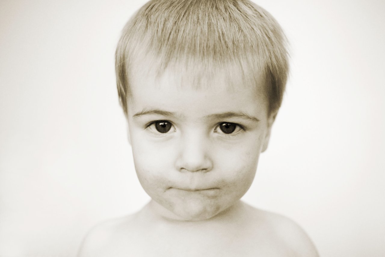 A young child with short hair looks directly at the camera with a neutral expression.