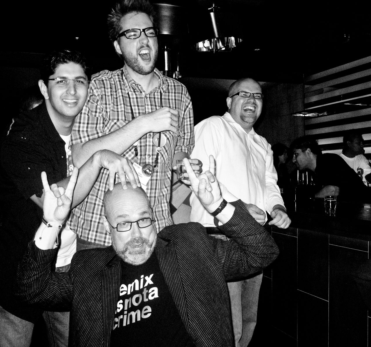 A group of people enjoying themselves at a party, with one person making rock hand gestures and another enthusiastically singing.