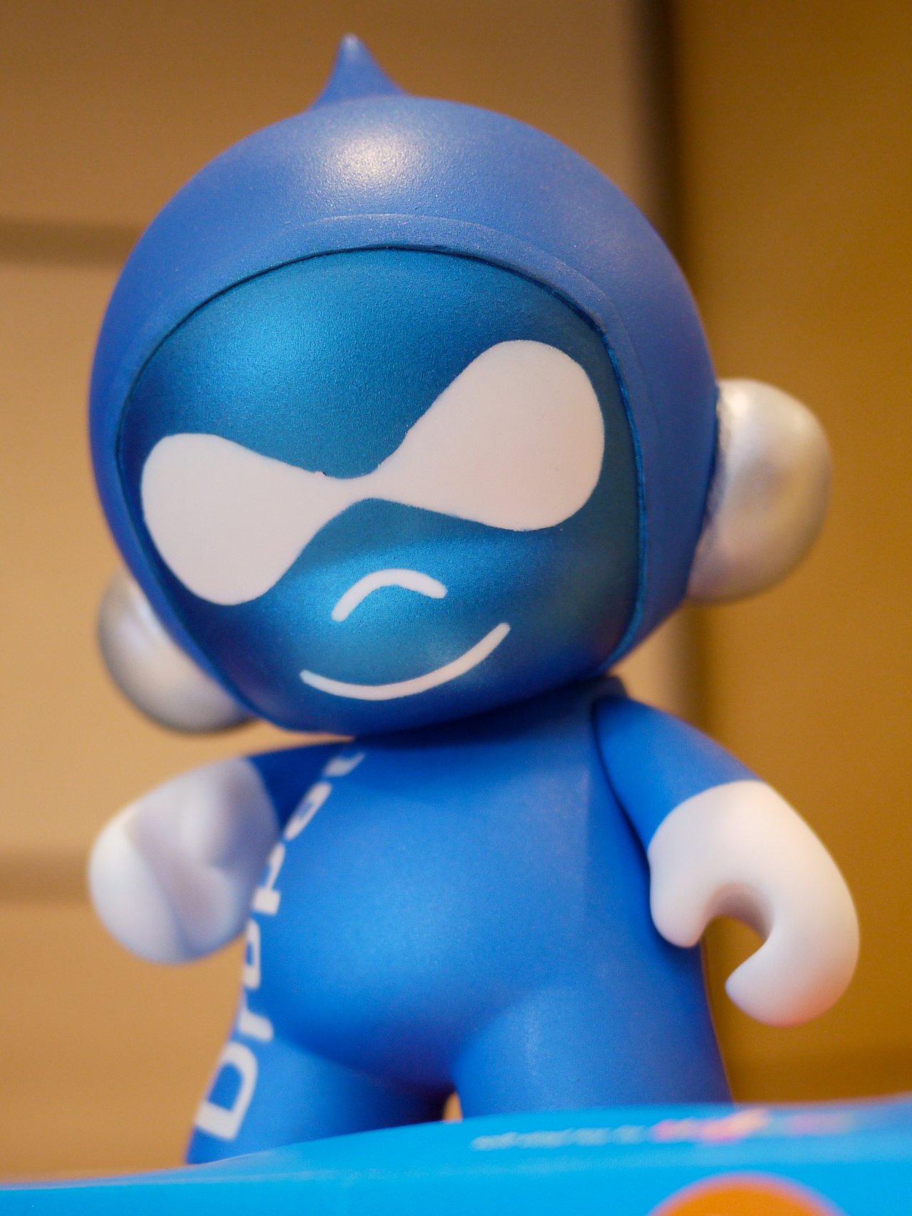 A close-up of a blue Druplicon figurine with a smiling face, representing the Drupal community at Drupalcamp Toronto.