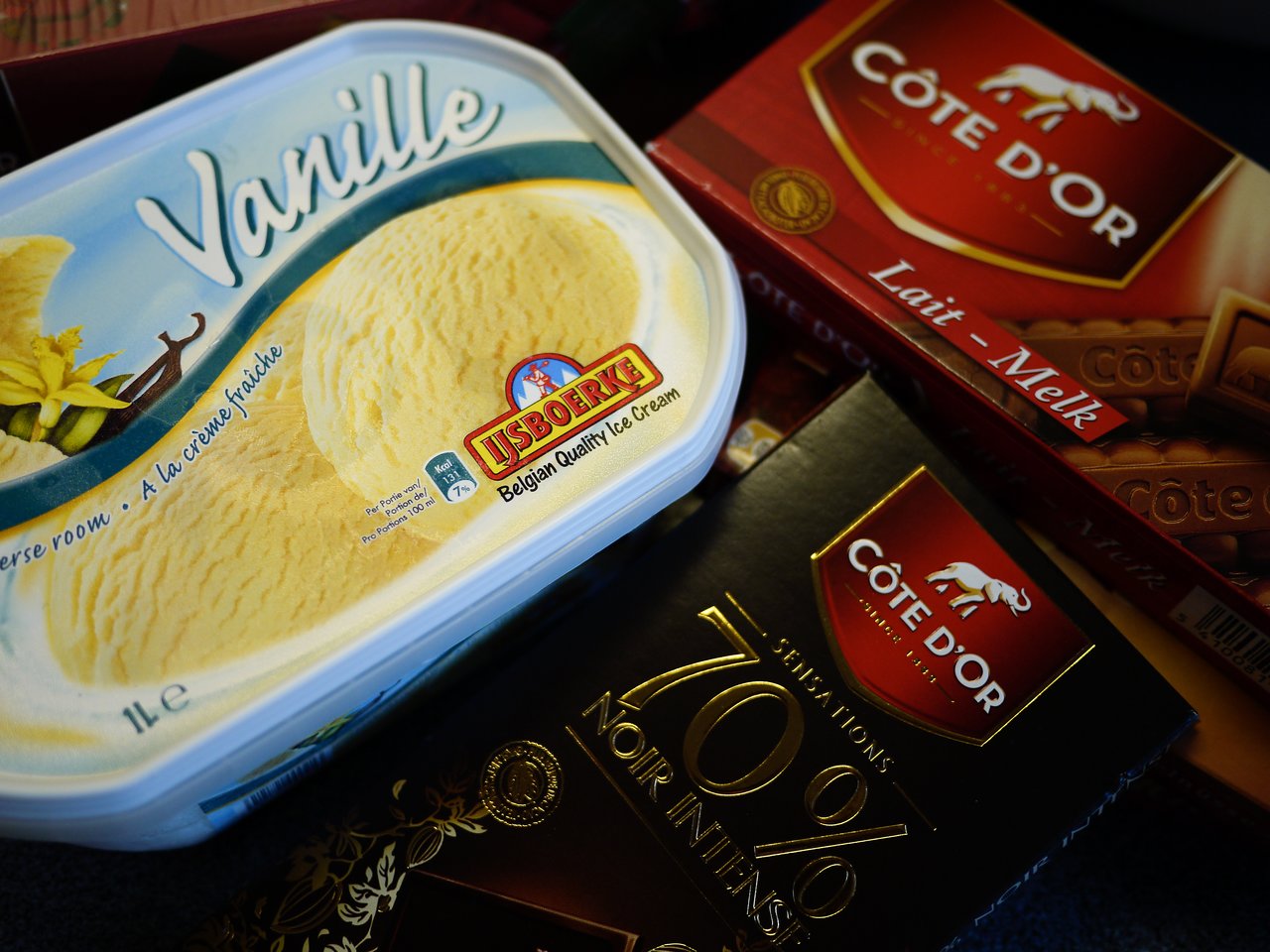 A container of vanilla ice cream and several Côte d'Or chocolate bars are placed together on a surface.