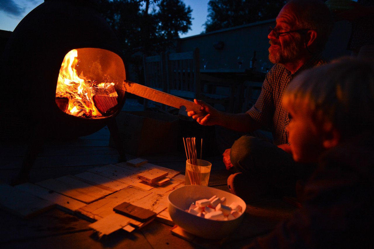 A man tends to a fire while a child watches.
