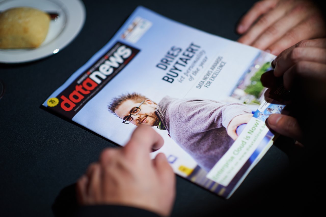 A person holds a Data News magazine featuring an ICT Personality of the Year on the cover.