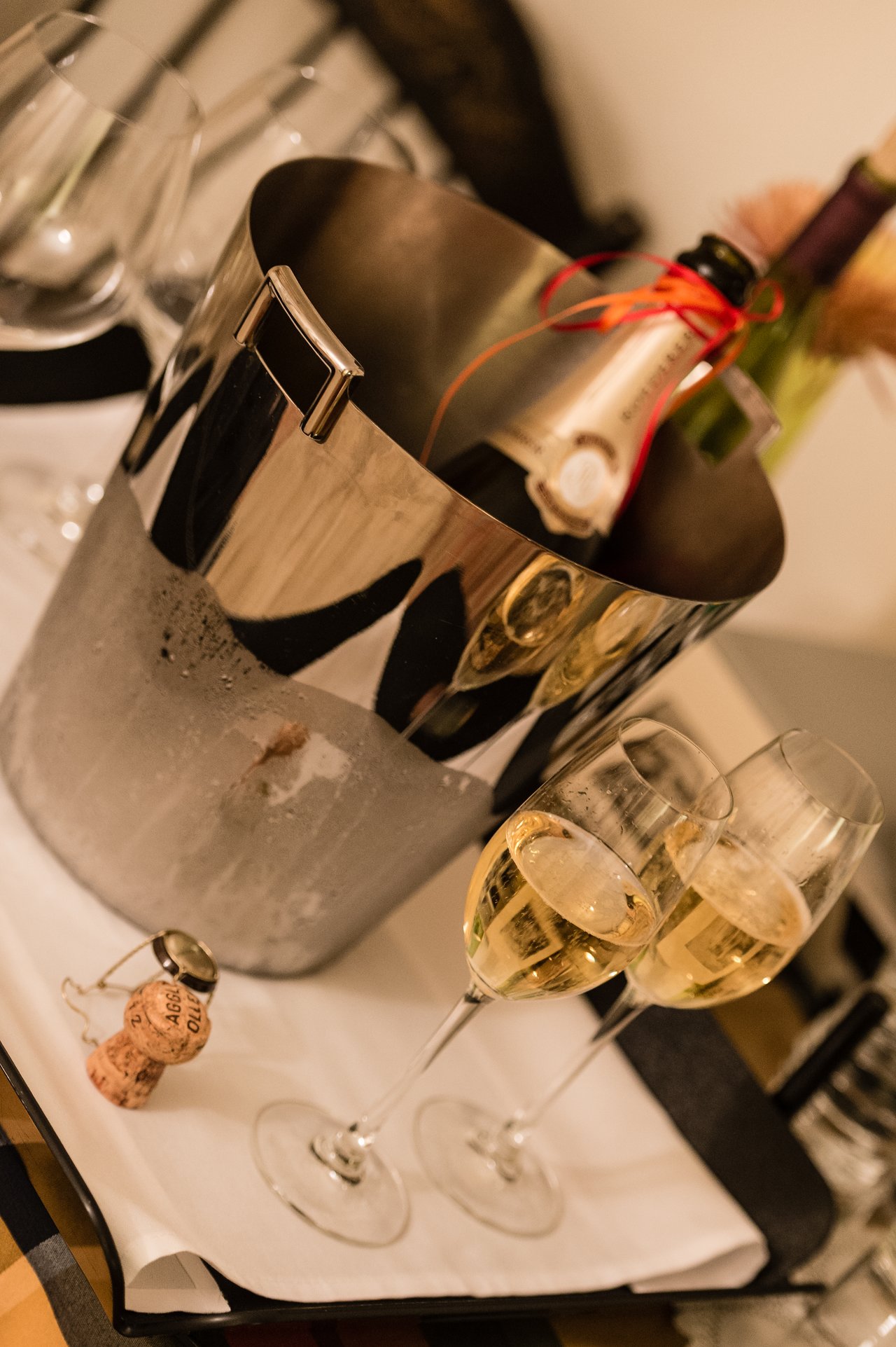A chilled champagne bottle in an ice bucket with two filled glasses on a tray, ready to serve.