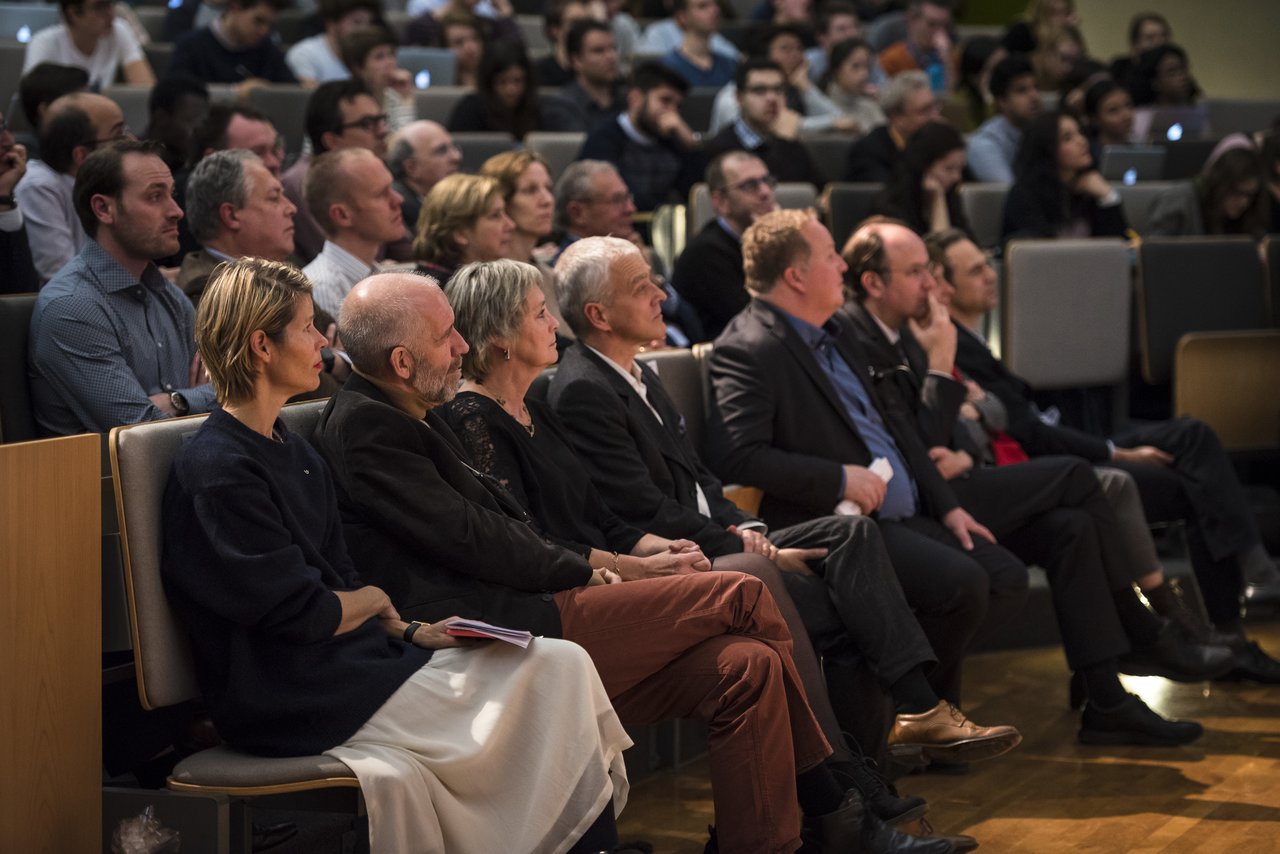 Audience members seated in the front row attentively watching a presentation at Antwerp University.
