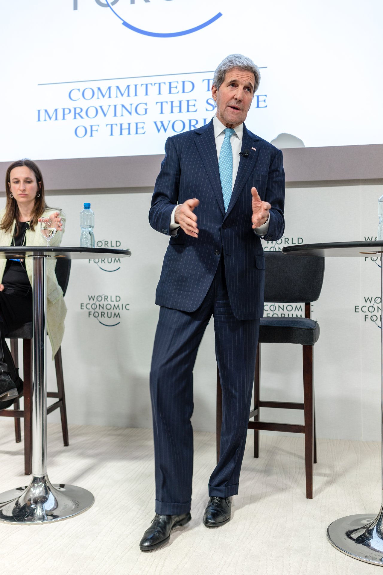 A man in a suit speaks and gestures while standing on stage at the World Economic Forum event.