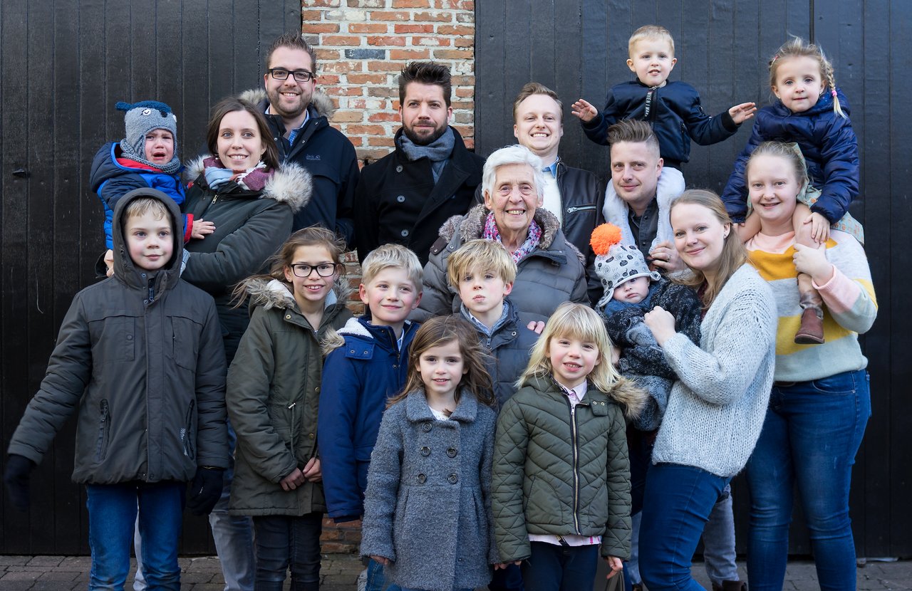 An elderly woman surrounded by family members of different ages, posing together for her ninetieth birthday celebration.