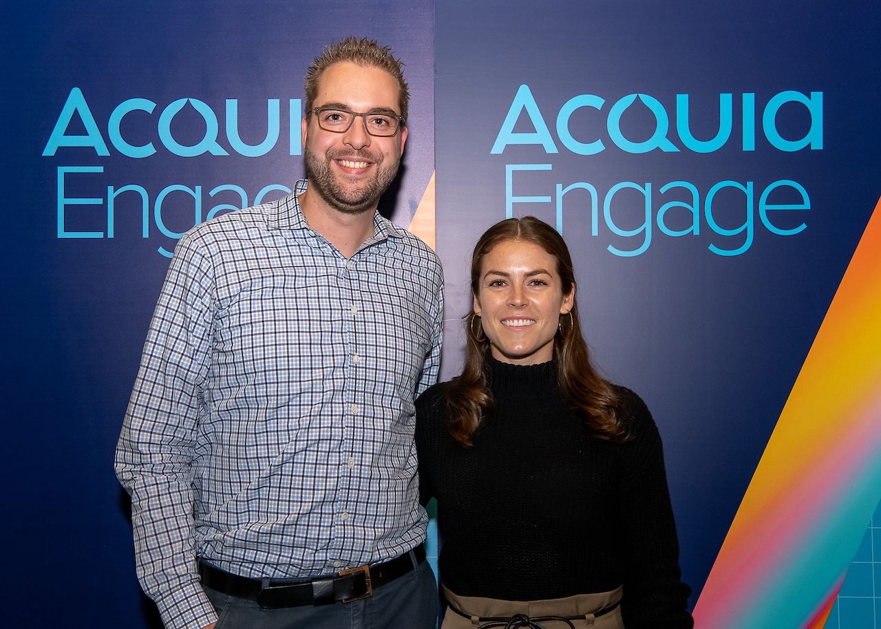 Two people smiling and posing for a photo at an Acquia Engage event.