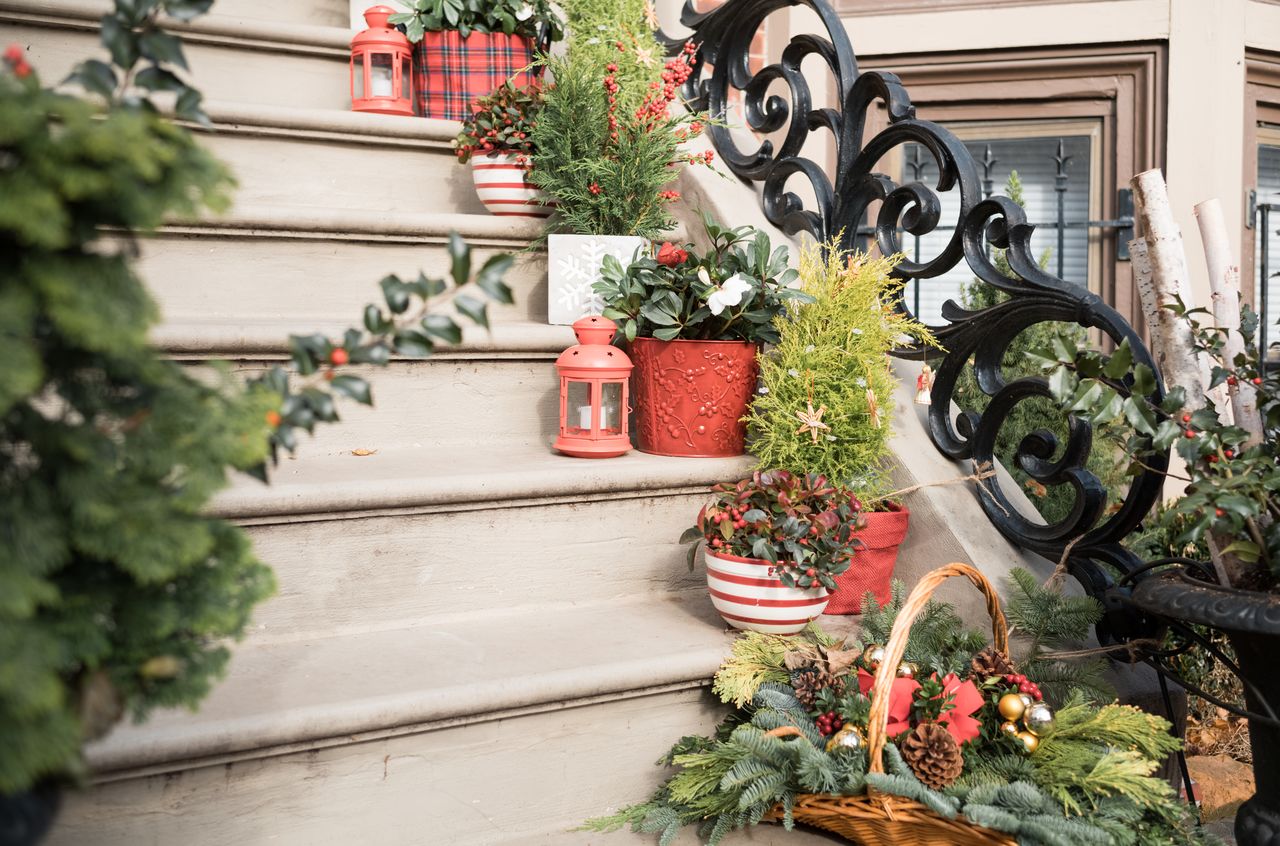 Stone steps decorated with potted plants, red lanterns, and a festive basket, with black wrought iron railings.