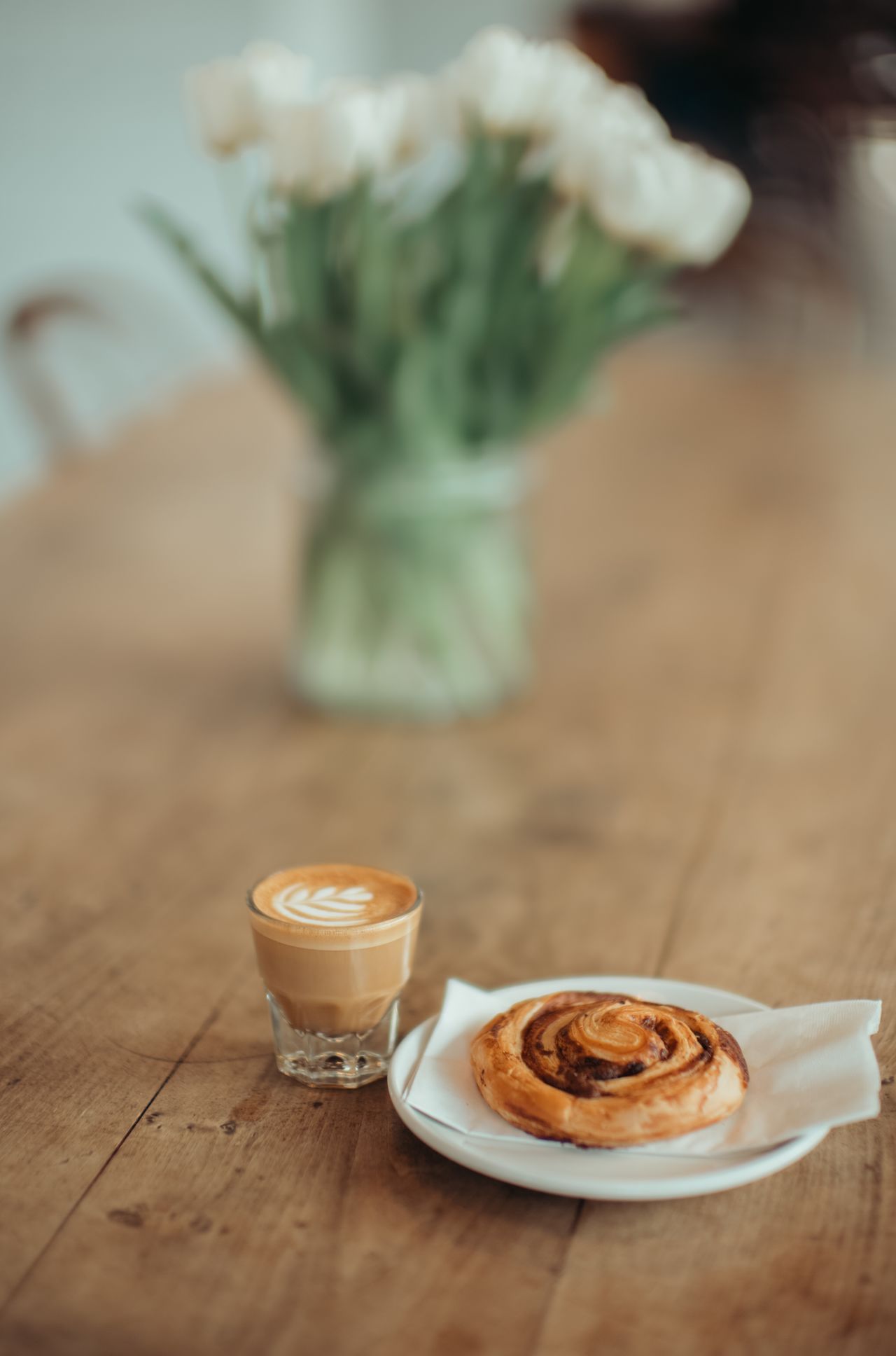A table with a cup of coffee and a pastry.