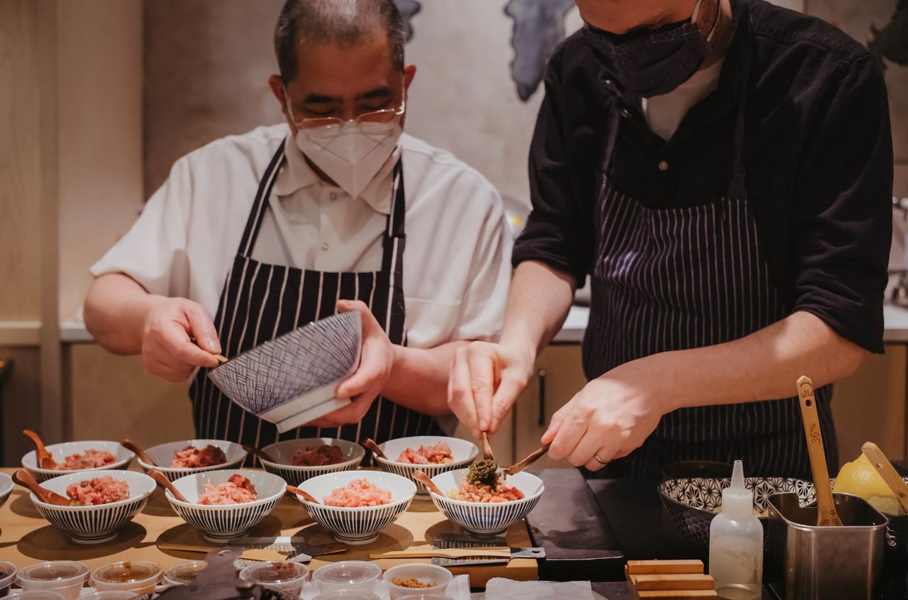 Two men in a kitchen preparing Japanese food.
