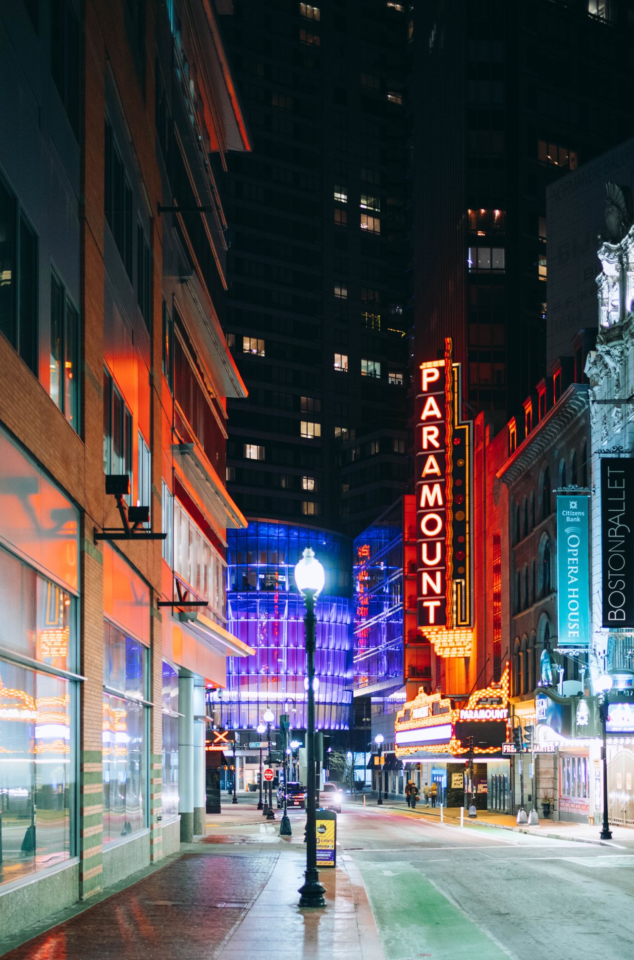 A street at night with a red and white sign that says "Paramount".