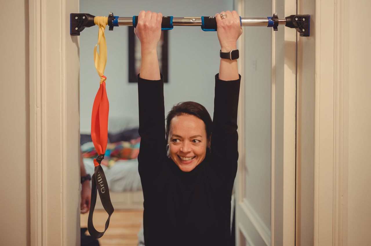 Vanessa hanging from a pull-up bar attached to a door frame.