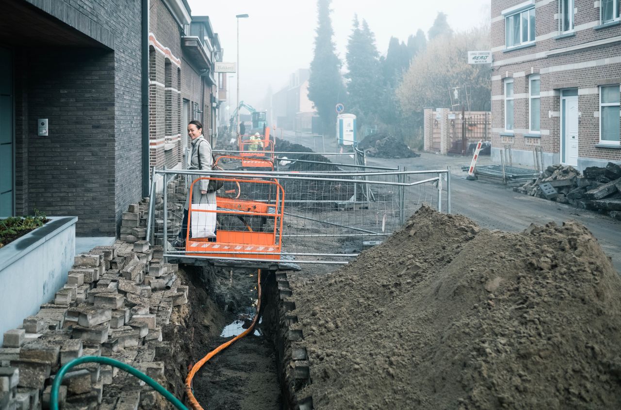 A woman standing on a sidewalk looking at construction.