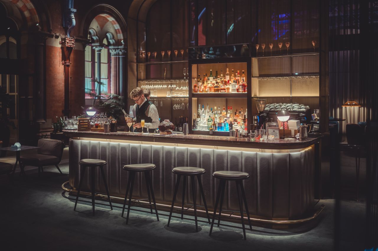 A bartender working behind the dimly-lit bar of a historic hotel.