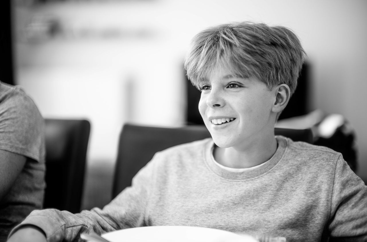 A boy sitting in a chair with a big smile on his face.