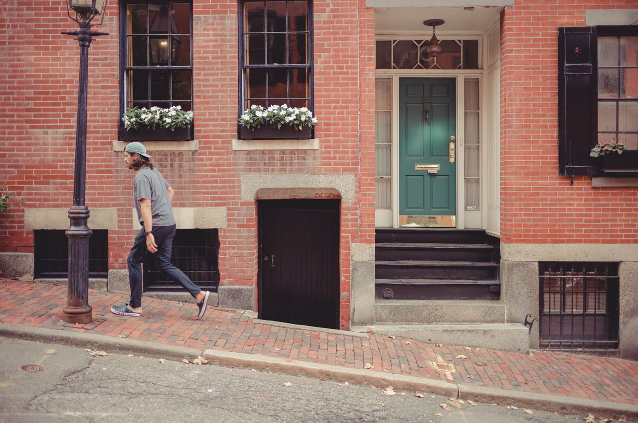 A person walking uphill, with an old house in the background.
