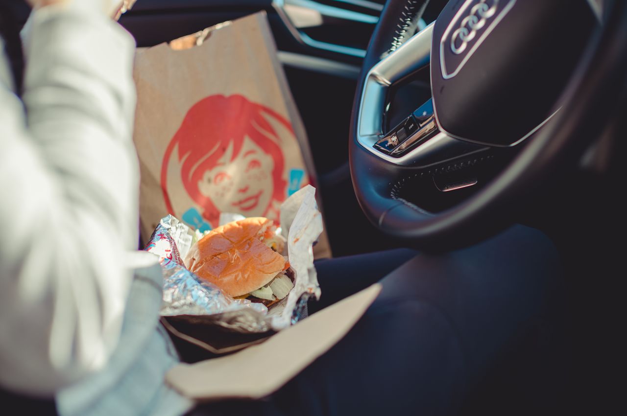 A person eating a burger in the car.