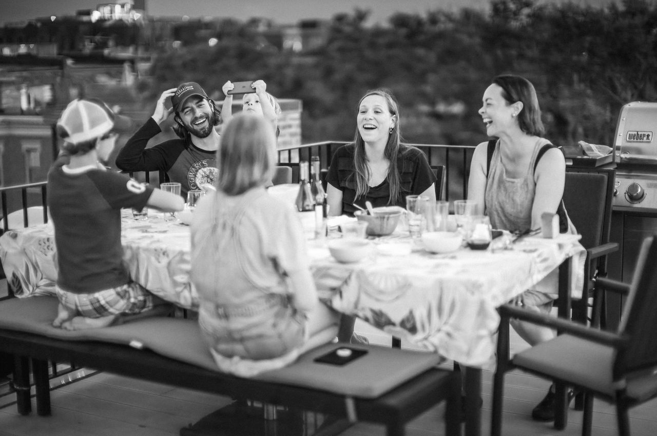 People laughing while sitting at a table and eating food.