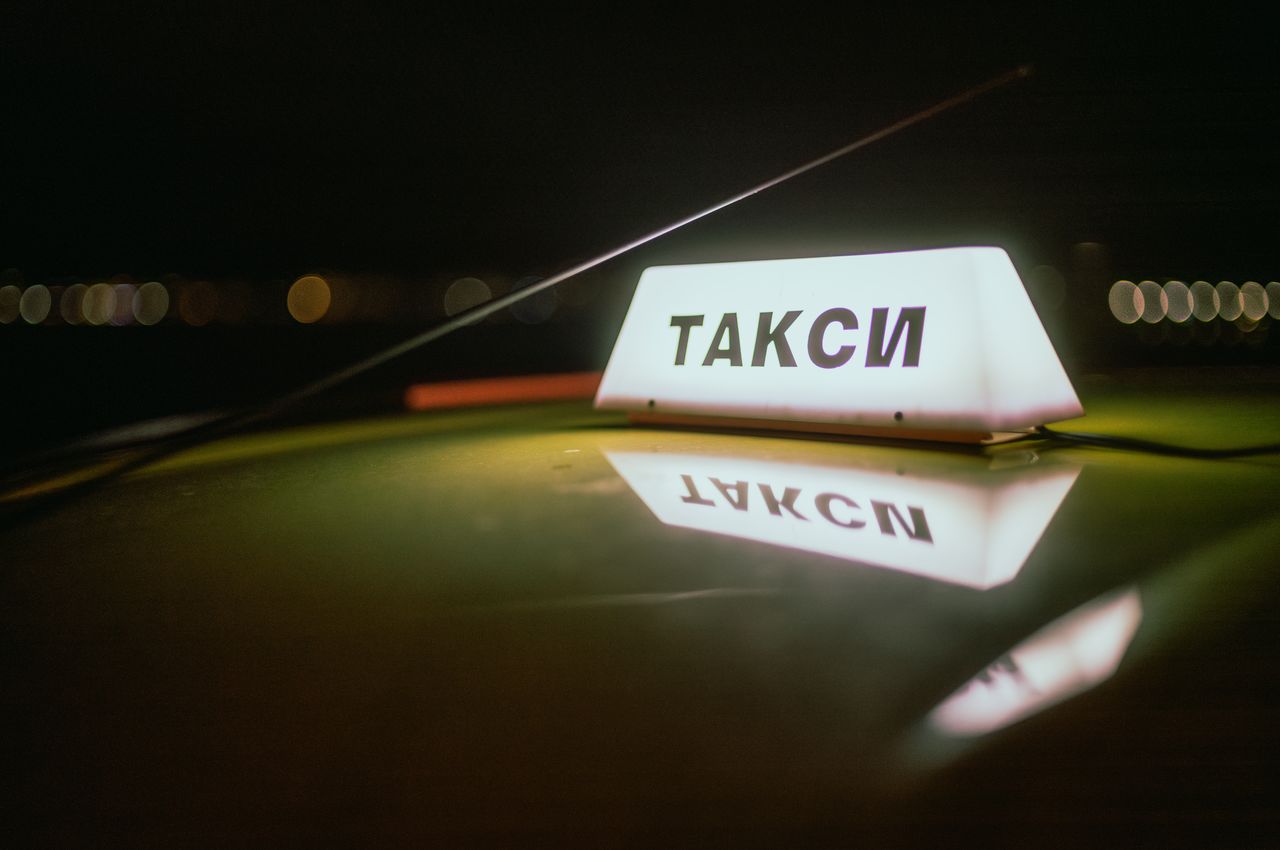 An illuminated taxi sign on the roof of a car.