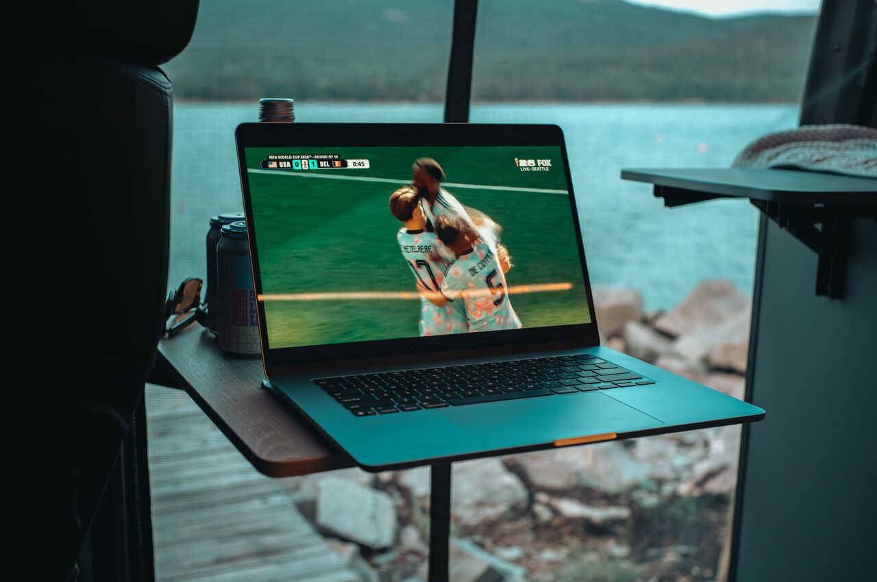 Open van doors looking out over the water in Acadia National Park, with a laptop showing the Belgium vs USA 2026 World Cup game.
