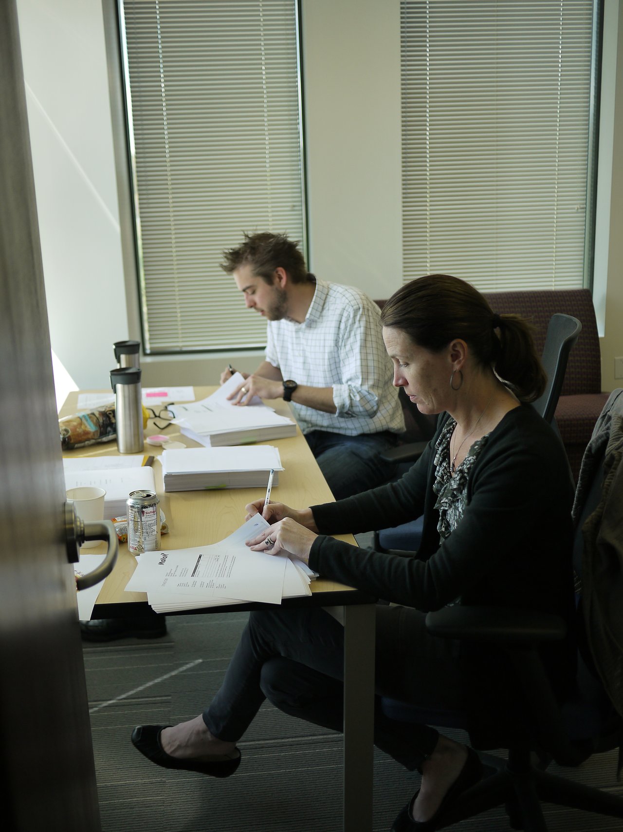 Two people sit at a table reviewing and signing documents, possibly related to the closing of Mollom.