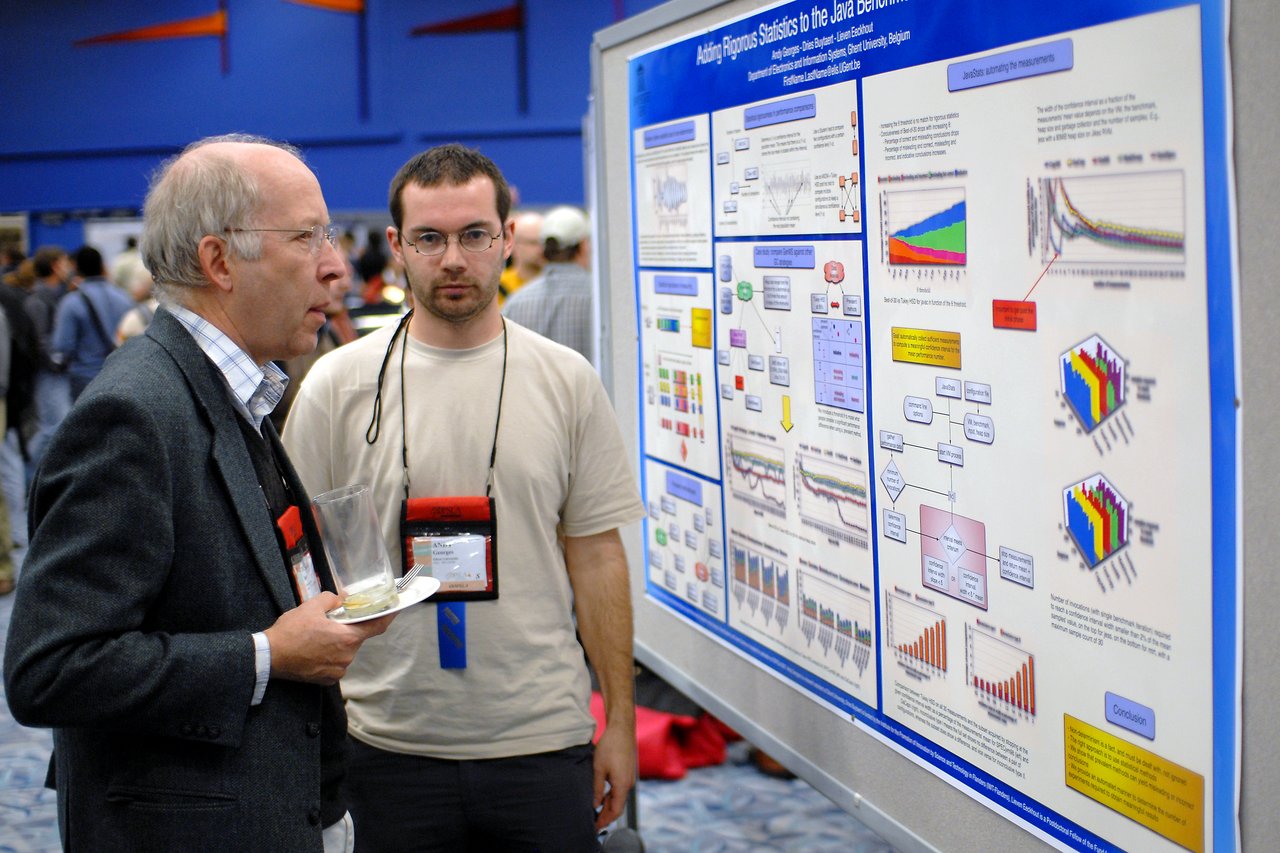 Andy presents a research poster while discussing data with an attendee at a conference.