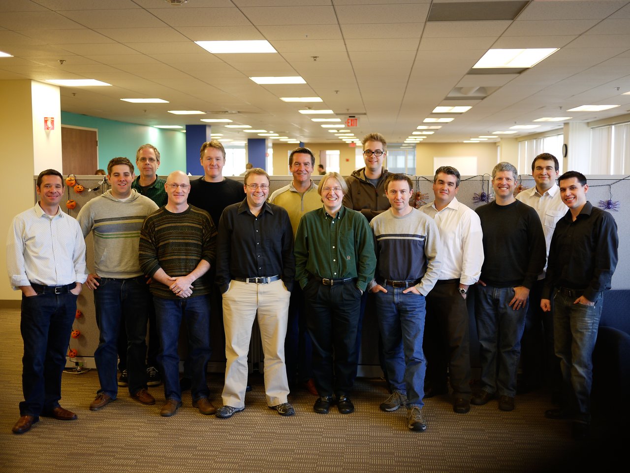 A group of fifteen people from the Acquia team pose together in an office on the first day of Movember 2010.