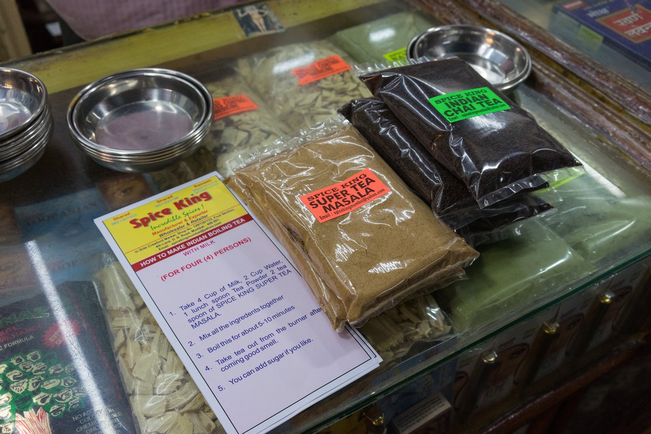 Packets of tea and spice mix on a glass counter with a printed recipe for making Indian tea.