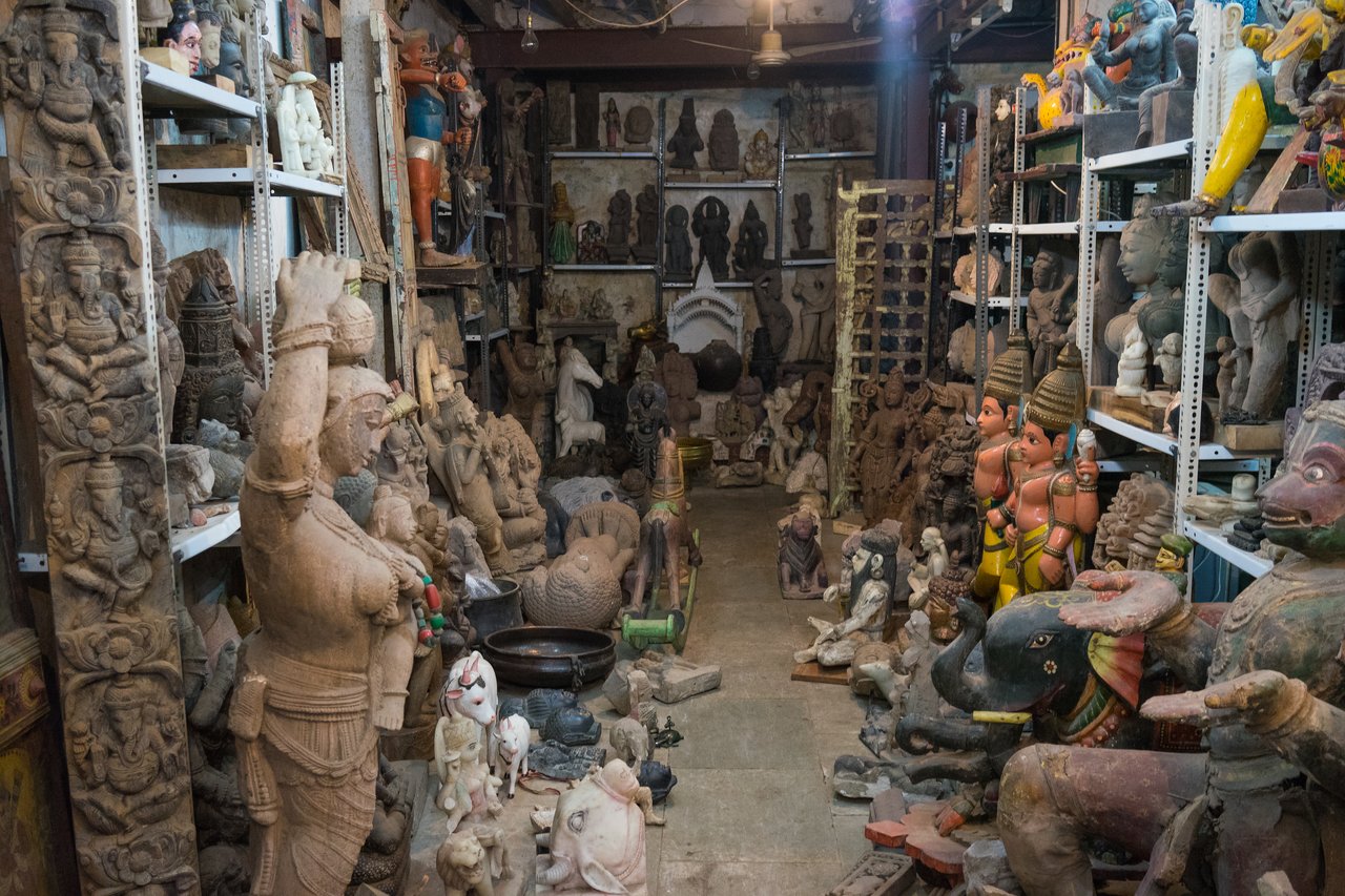 A room filled with various stone and wooden statues, including human figures, animals, and deities, arranged on shelves.