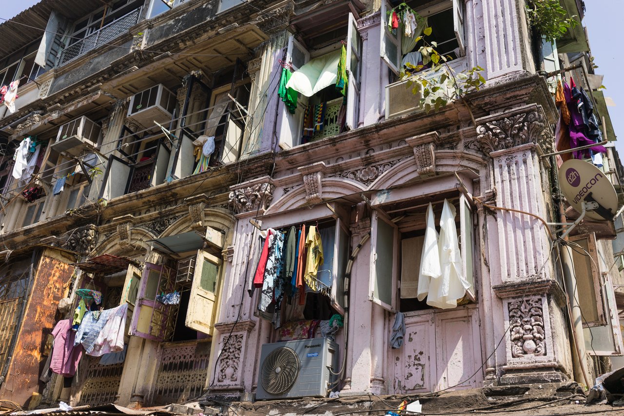 Old apartment building with open windows and clothes hanging outside to dry.