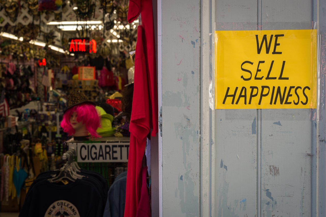 A yellow sign on a shop door reads "WE SELL HAPPINESS", with colorful merchandise visible inside the store.