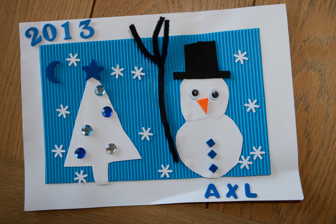 A handmade New Year 2013 card with a snowman, tree, and snowflakes on a blue background.
