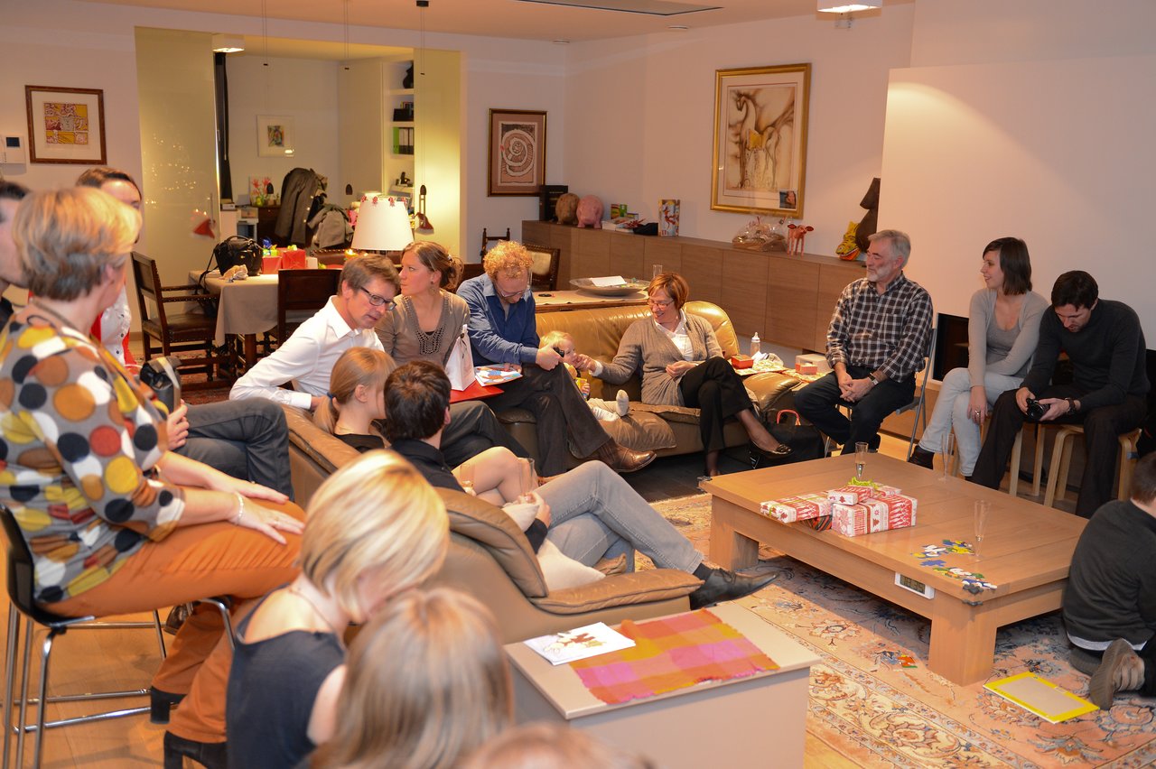 A group of people gathered in a living room, talking and enjoying a New Year's party.