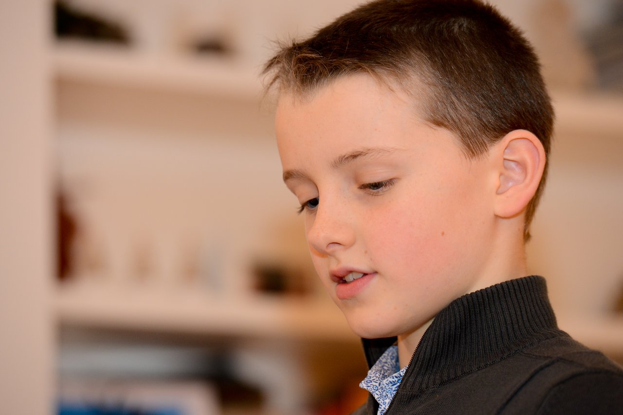 A young boy in a black sweater looks down with a focused expression at a New Year's party.