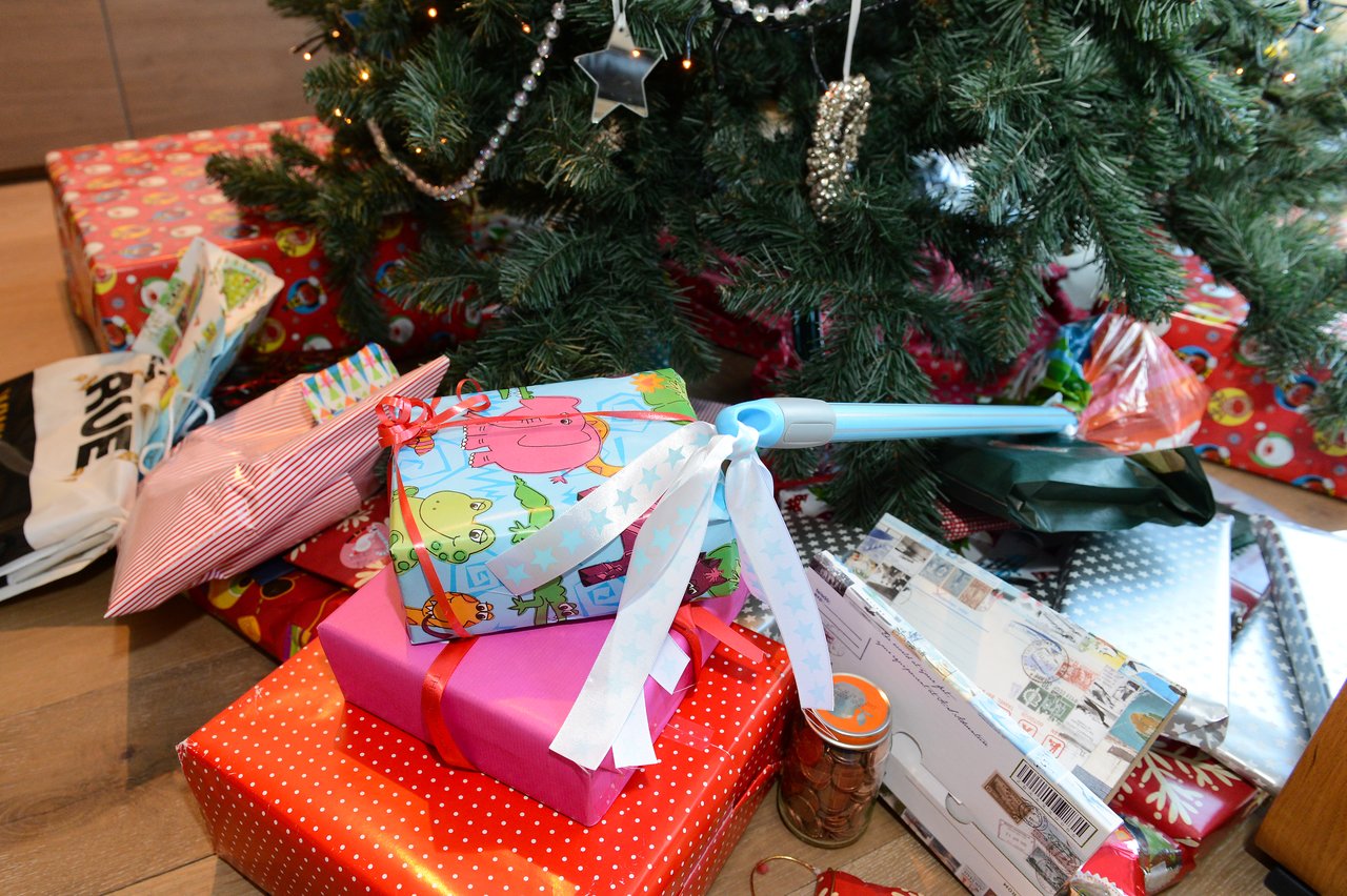 A decorated Christmas tree with wrapped gifts underneath, featuring colorful paper and ribbons.