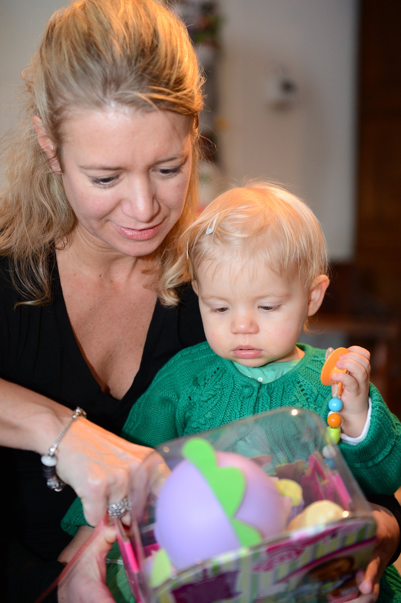 A woman and a baby open a toy package together.