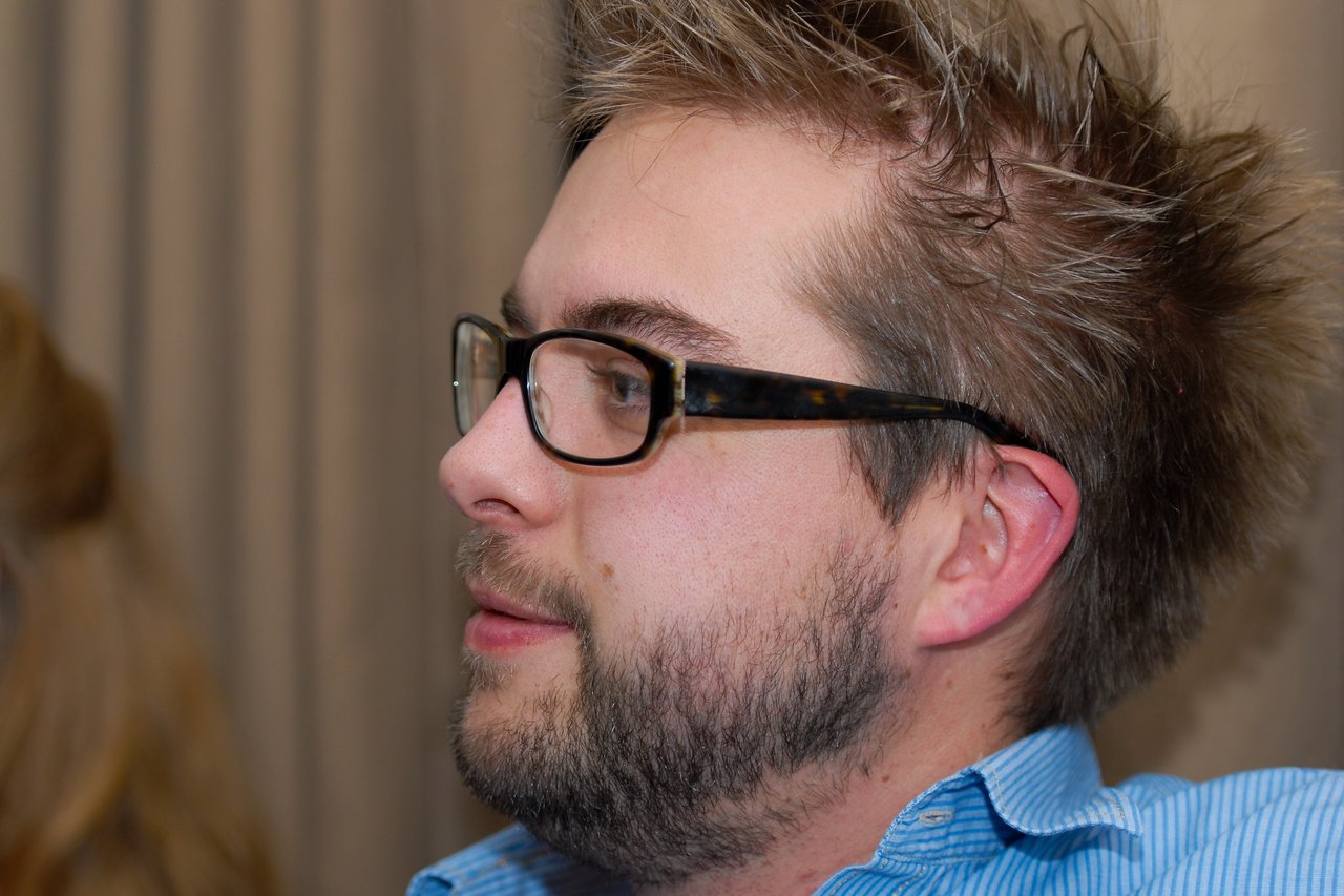 A man with glasses and a beard looks to the side at a New Year's Eve party.