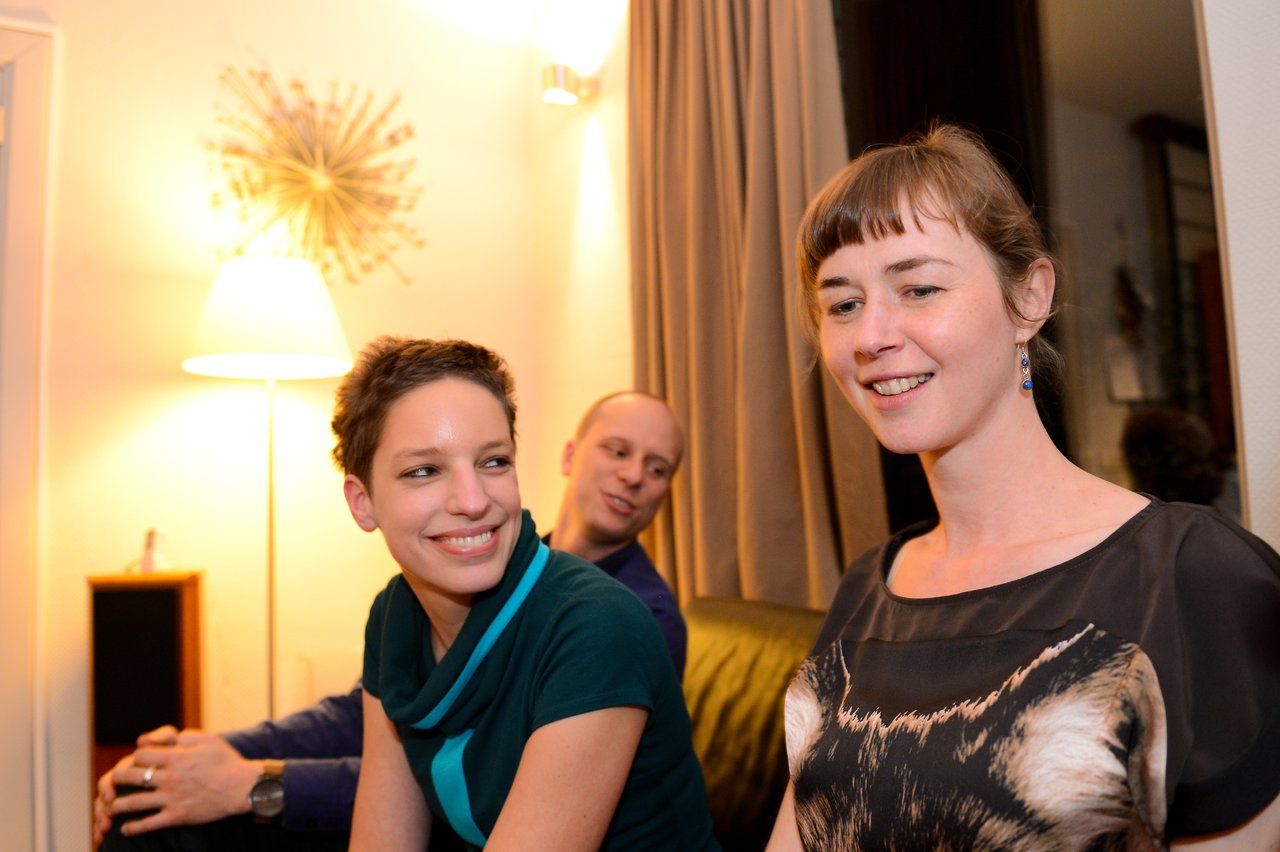 Three people sitting in a living room, smiling and talking during a New Year's Eve party.