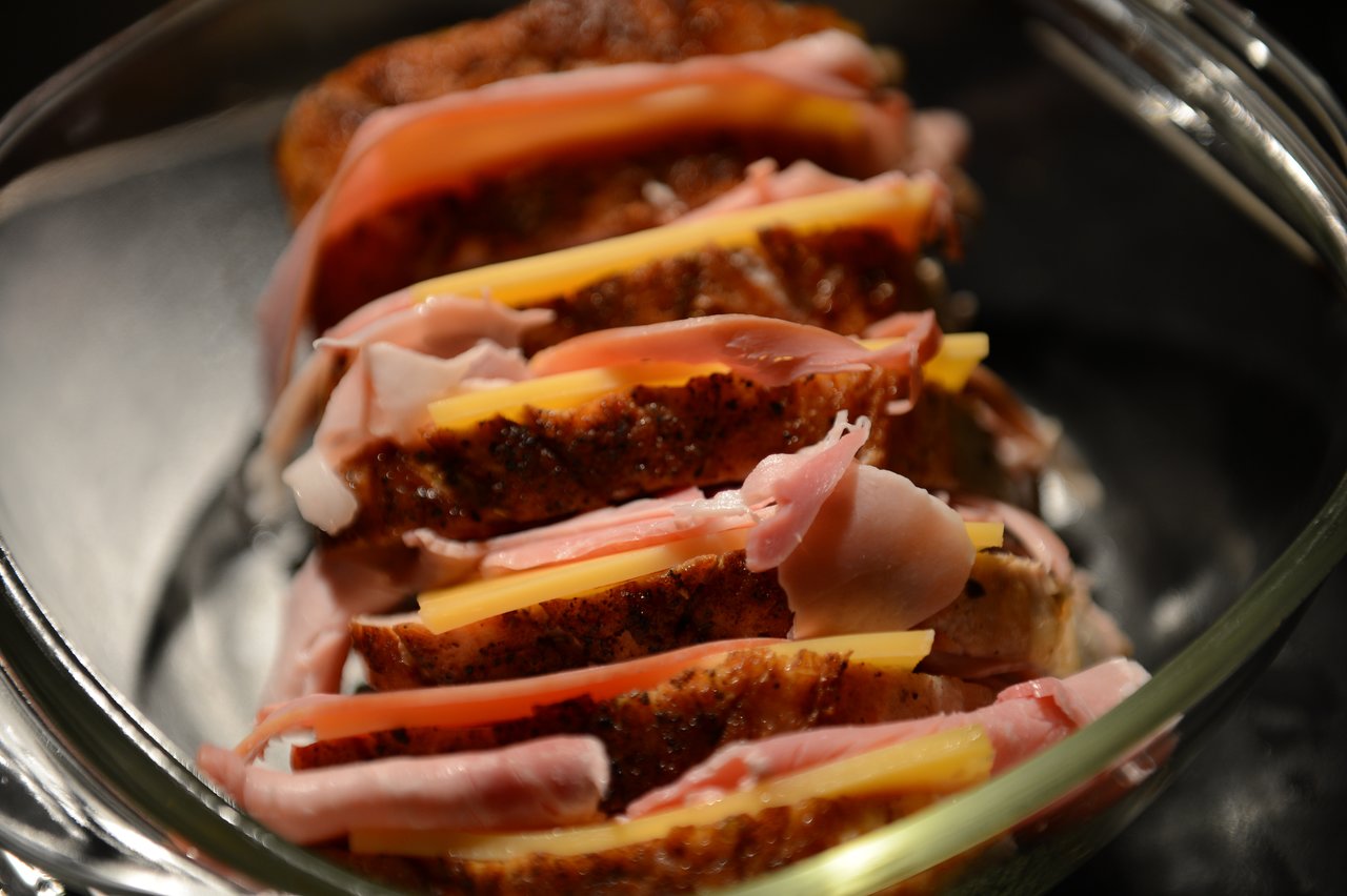 Sliced meat stuffed with ham and cheese in a glass baking dish, ready to be served.
