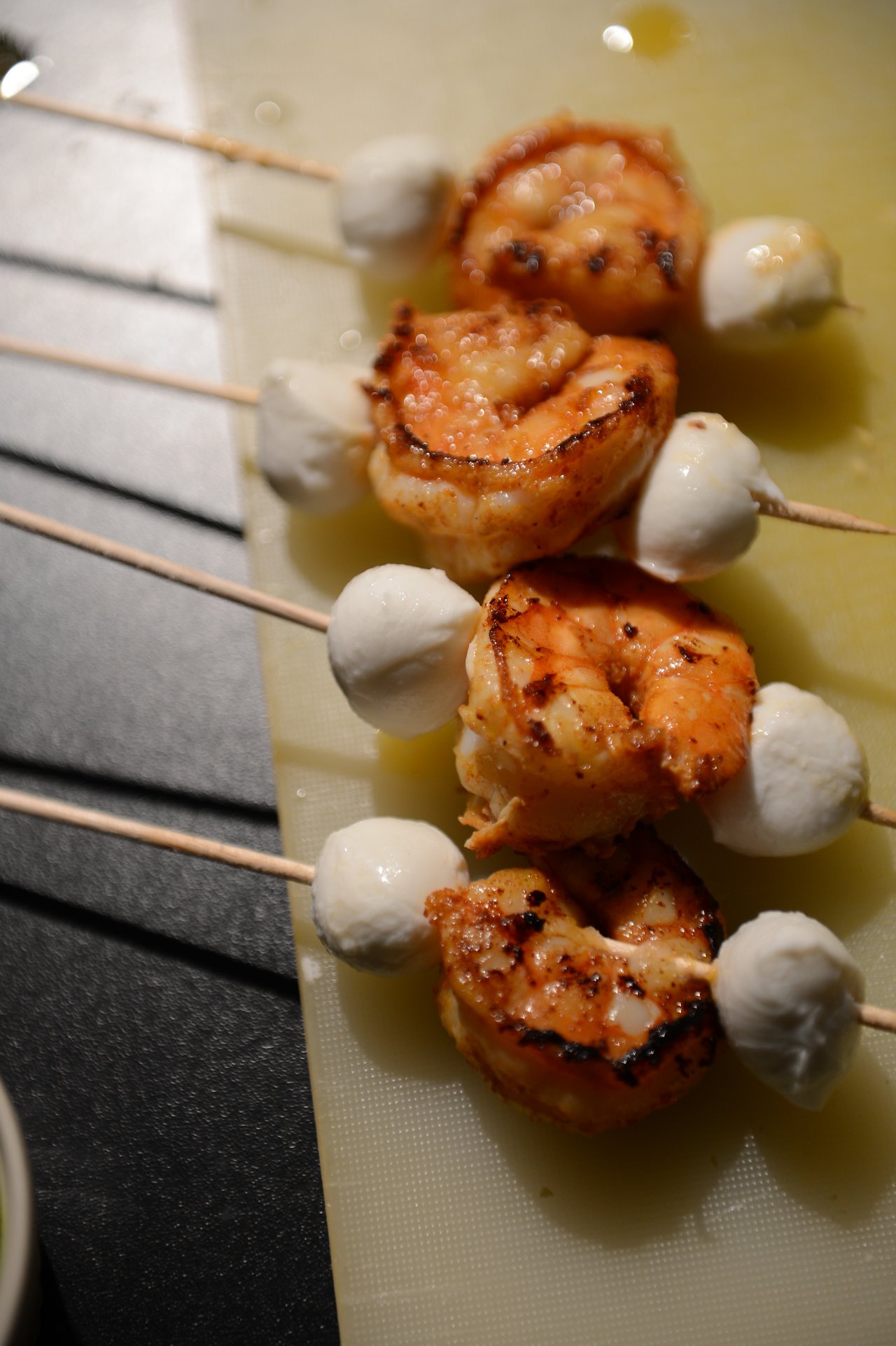 Grilled shrimp and mozzarella skewers on a cutting board, prepared for a New Year's Eve party.