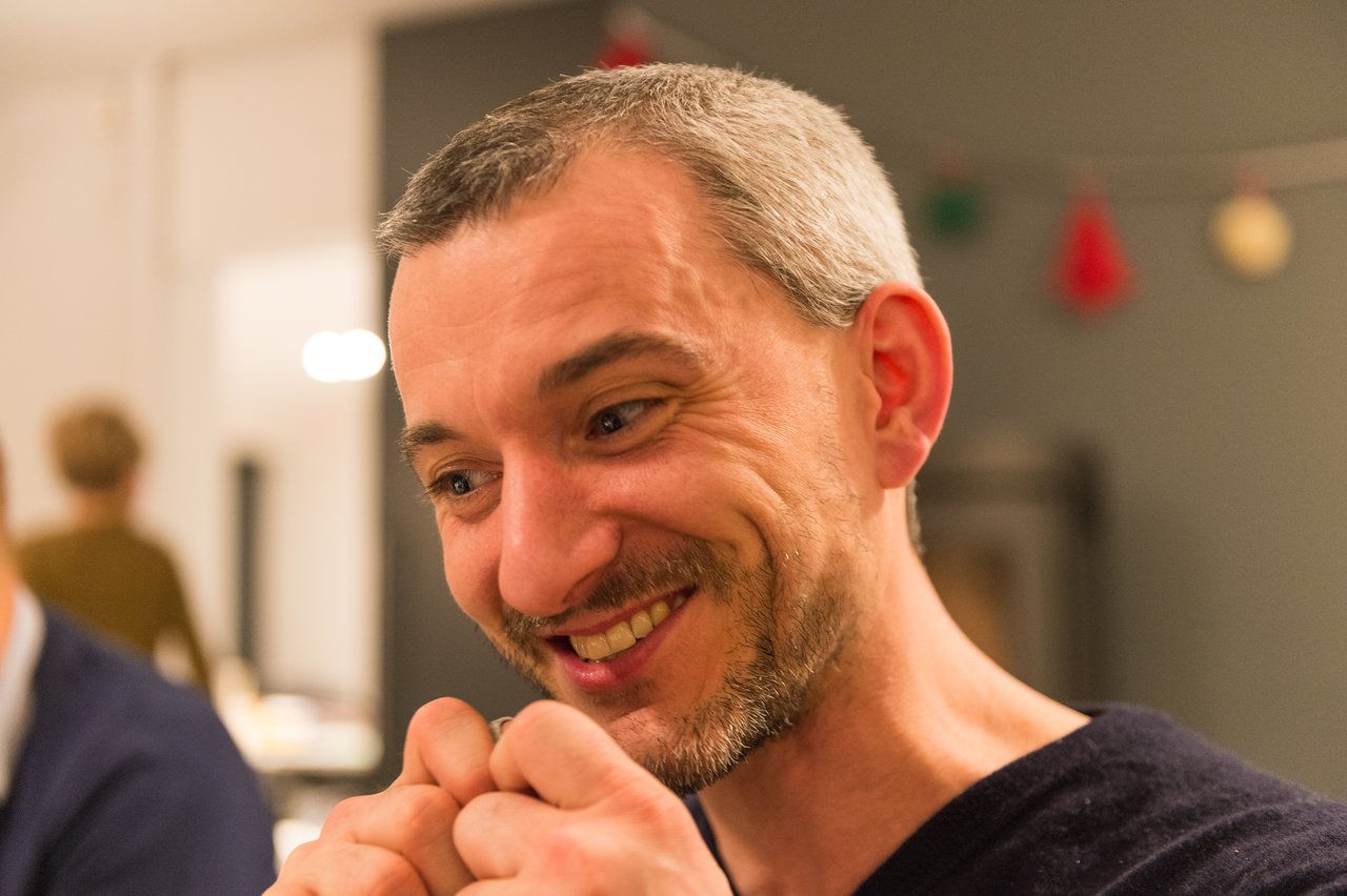 A smiling man at a New Year's Eve party, looking engaged in conversation with hands clasped together.