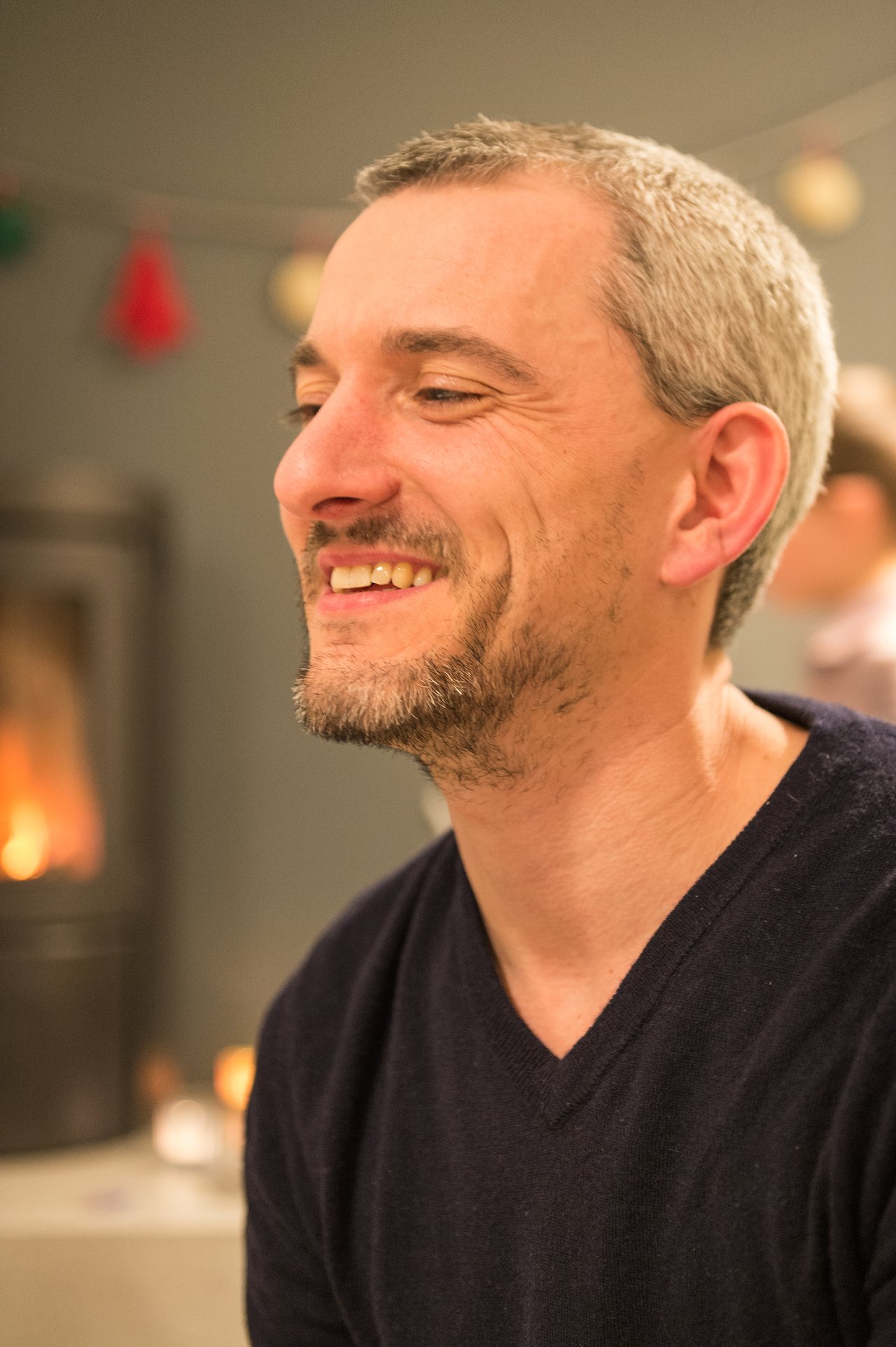 A man with short gray hair and a beard smiles at a New Year's Eve party.